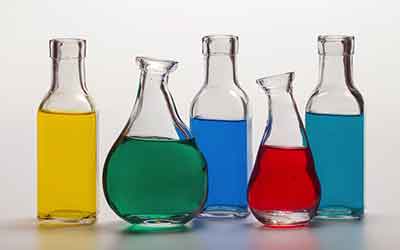 Photo of glass bottles filled with colored liquids. Still life paintings hone our drawing skills.